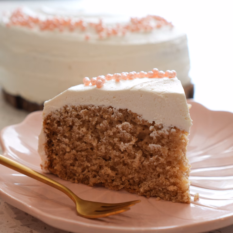 Slice of gluten-free vegan vanilla cake with vanilla frosting on a pink plate