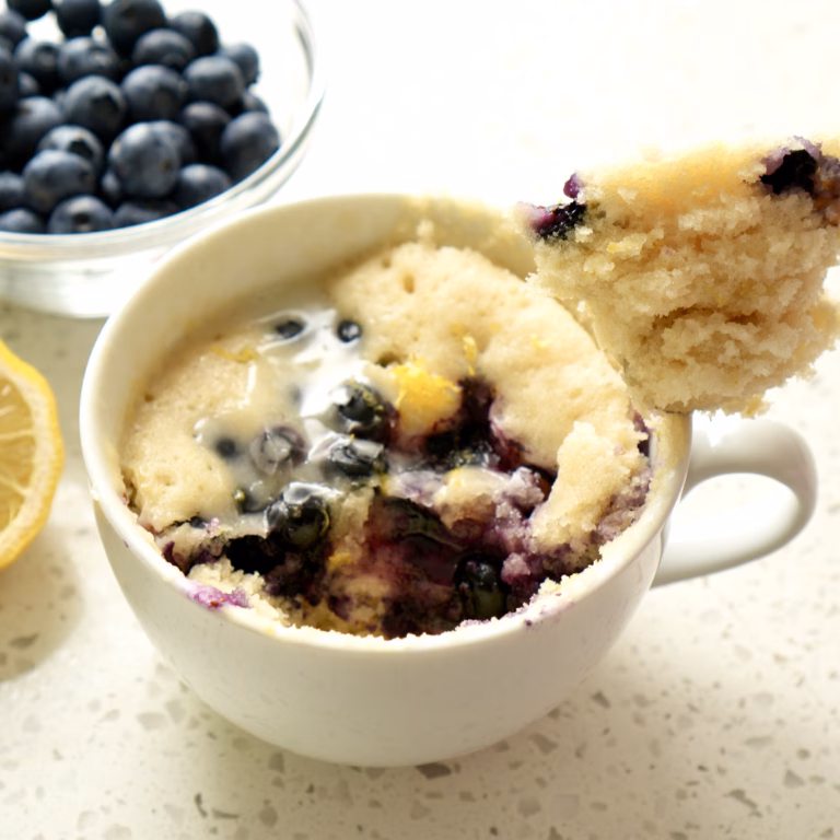 Vegan lemon blueberry mug cake with lemon glaze in a mug