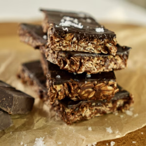 Stacked no-bake chocolate oat bars with dark chocolate and flaky sea salt