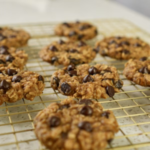 Banana oat cookies with chocolate chips cooling on a wire rack, shown in a square crop.